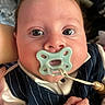 Logan is registered to the contest to win money with this photo: baby, pacifier, close_up, face, child, infant, cute, clothing, vest, hand, skin, eyes, expression, indoors, person, young_child, portrait, head, soft_lighting, pinstriped