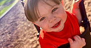 Vinny is registered to the contest to win money with this photo: child, toddler, swing, playground, outdoor, happy, smile, red_shirt, sunlight, park, play, fun, young, face, holding, metal_chain, grass, blur, casual_clothing, daytime