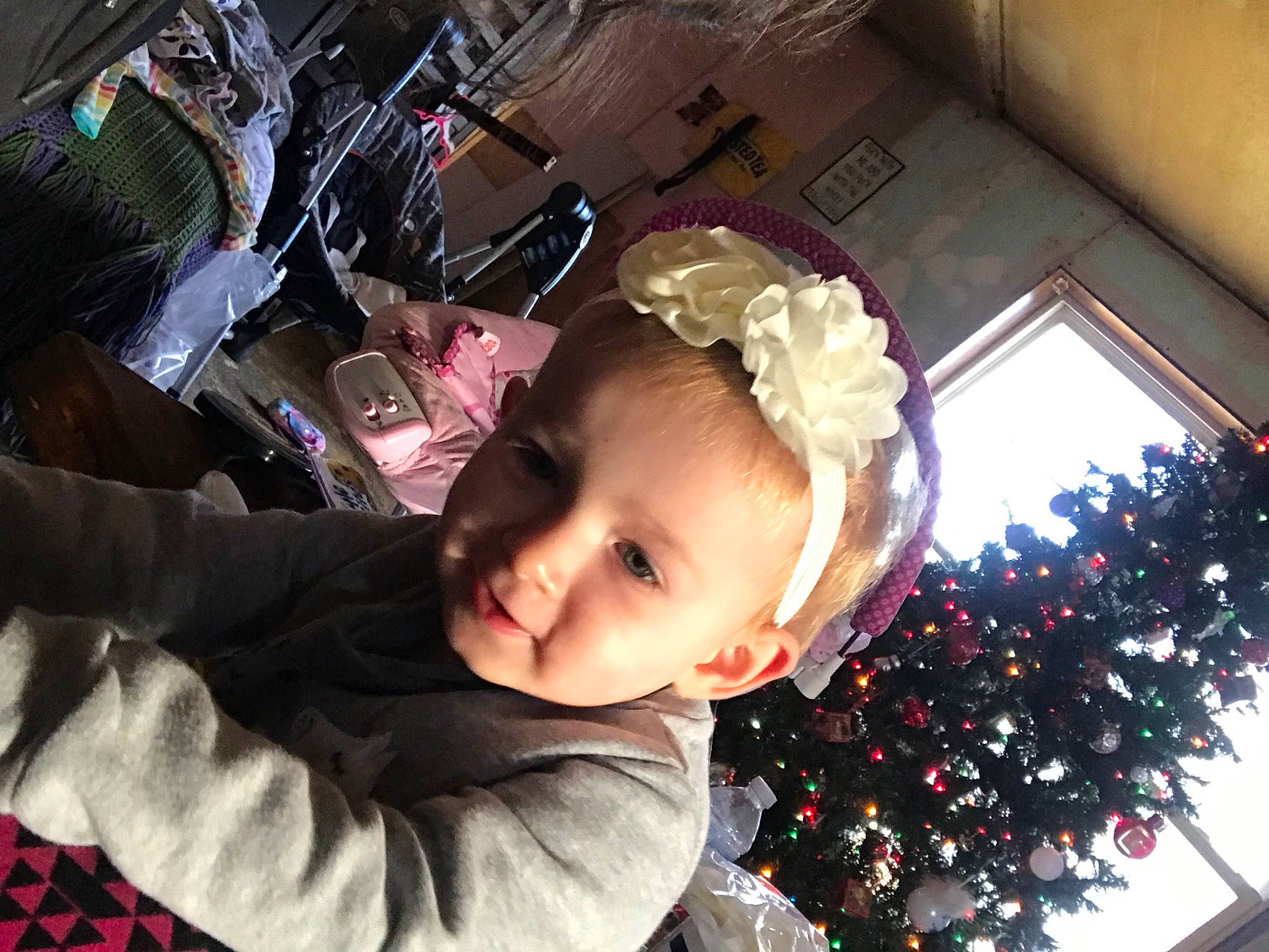 Lucy is registered to the contest to win money with this photo: baby, child, christmas, christmas_ornament, christmas_tree, conifer, event, fun, happy, holiday, holiday_ornament, interior_design, ornament, person, photograph, smile, snapshot, toddler, tree, window