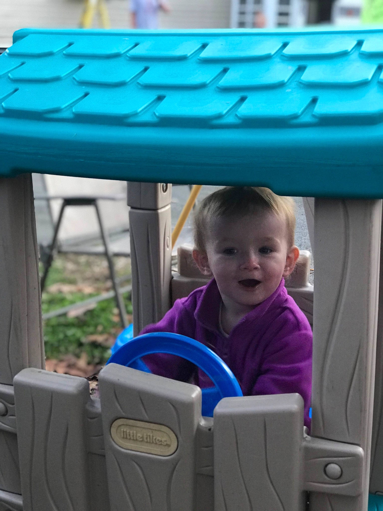Lucy is registered to the contest to win money with this photo: baby, baby_toddler_clothing, blue, child, electric_blue, fun, grass, green, leisure, motor_vehicle, outdoor_furniture, outdoor_table, person, plant, product, public_space, recreation, smile, t_shirt, table