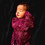 baby, sleeping, infant, onesie, maroon, floral_pattern, cozy, portrait, peaceful, child, cute, soft_lighting, dark_background, newborn, resting, clothing, face, head, person, indoors