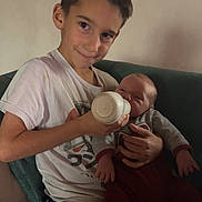 Miguel a rejoint le concours — aidez-le/la à gagner de superbes lots ! child, baby, feeding, bottle, smile, couch, blanket, toddler, boy, indoors, clothing, person, sitting, cute, family, home, relaxing, young, infant, care