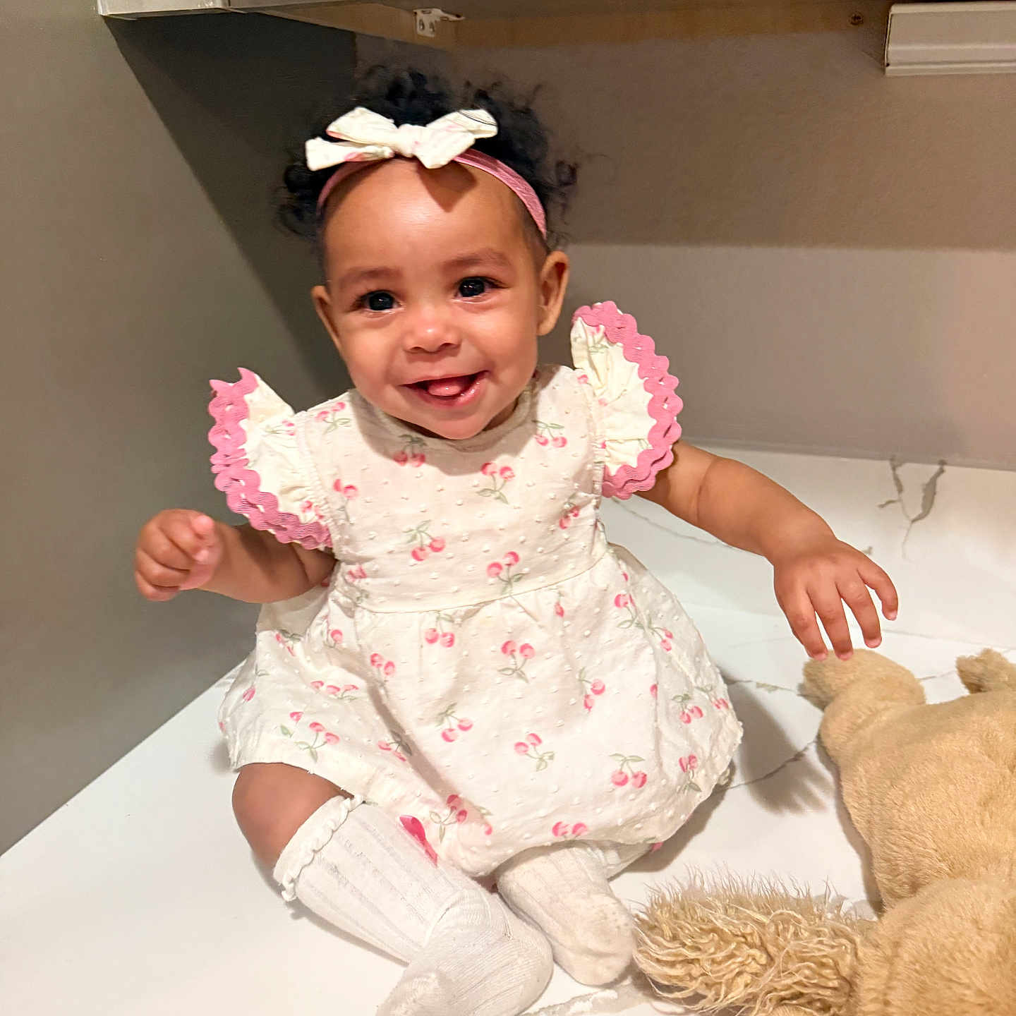Bria is registered to the contest to win money with this photo: baby, child, smiling, dress, headband, socks, teddy_bear, toy, marble_surface, happy, cute, indoor, person, infant, pink, white, playful, portrait, sitting, cuddly_toy