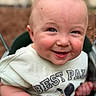 Caspian is registered to the contest to win money with this photo: baby, child, smile, swing, outdoor, shirt, cartoon, face, blue_eyes, rosy_cheeks, cute, infant, playful, happy, closeup, skin, head, expression, small_scratch, person