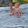 Rosalyn is registered to the contest to win money with this photo: baby, infant, child, sitting, outdoors, grass, tarp, blanket, adult, legs, reaching, curious, profile, barefoot, summer, daylight, portrait, playtime, family, water_drops