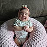 baby, infant, child, smiling, portrait, sitting, headband, bow, floral_outfit, onesie, pink_pillow, plush, cushion, leather_sofa, indoor, home, happy, hands_clasped, centered, closeup
