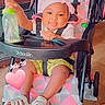 baby, child, infant, stroller, smiling, bow, headband, bottle, sandal, seated, portrait, indoors, playful, happy, baby_clothing, green_shorts, pink, heart_sticker, date_text, furniture