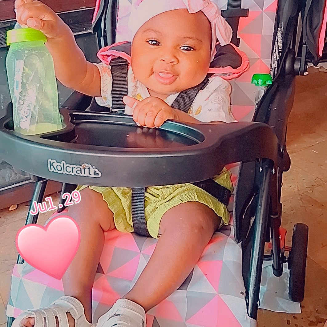 Caloni joined the competition — help win amazing prizes! baby, child, infant, stroller, smiling, bow, headband, bottle, sandal, seated, portrait, indoors, playful, happy, baby_clothing, green_shorts, pink, heart_sticker, date_text, furniture