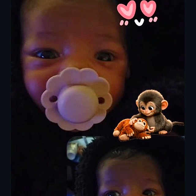 Paris is registered to the contest to win money with this photo: baby, pacifier, infant, face, closeup, blanket, cute, child, portrait, dark_background, expression, eyes, cartoon_monkeys, text_overlay, love, adorable, newborn, sleepwear, head, cozy