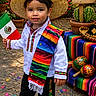 child, boy, sombrero, mexican_flag, traditional_clothing, serape, confetti, outdoor, celebration, cinco_de_mayo, colorful, maracas, cactus, sign, festive, smiling, street, party, holiday, decorations