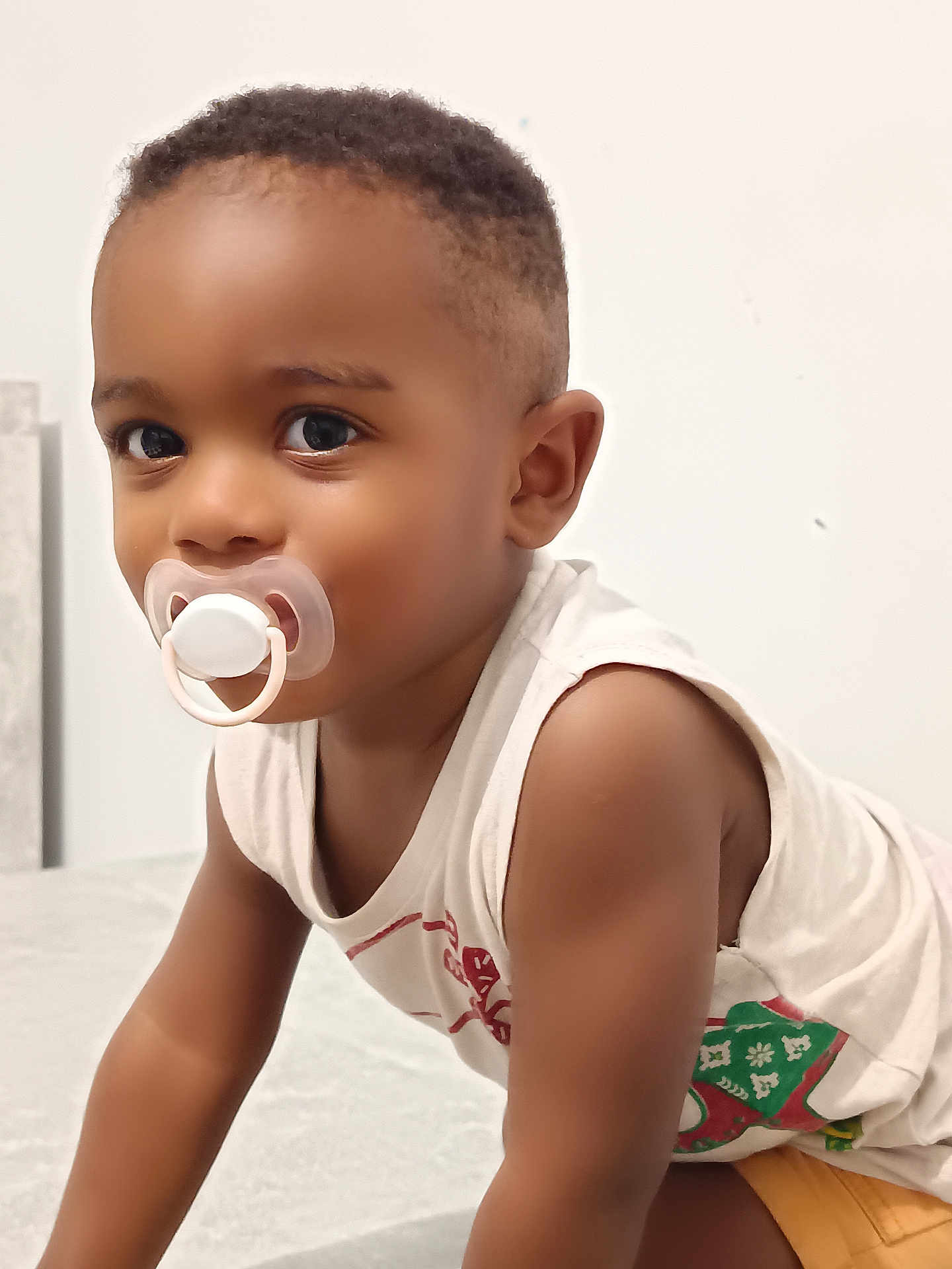 Bachir a rejoint le concours — aidez-le/la à gagner de superbes lots ! toddler, child, pacifier, curious, indoor, white_background, short_hair, sleeveless_shirt, brown_skin, portrait, closeup, cute, young_child, looking, baby, infant, expression, face, arm, casual_clothing