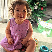 Jelilah joined the competition — help win amazing prizes! baby, blue_toy, carpet, child, christmas_tree, curly_hair, cute, decorations, green_toy, happy, holiday_decor, home, indoor, infant, natural_light, playtime, purple_dress, sitting, smiling, toys