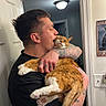 man, cat, tattoo, indoor, door, light, orange_cat, white_cat, holding, affection, pet, animal, feline, human, portrait, wall, sign, expression, close_up, casual
