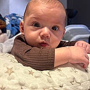 Emilio a rejoint le concours — aidez-le/la à gagner de superbes lots ! baby, brown_clothing, child, closeup, cozy, cushion, cute, expression, eyes, face, hand, head, indoor, infant, portrait, resting, skin, soft_lighting, star_pattern, young