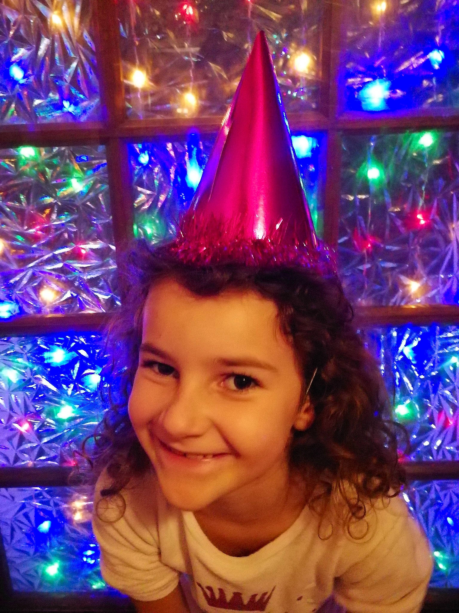 Leïla participe au concours pour gagner de l'argent avec cette photo : baby_toddler_clothing, christmas, christmas_decoration, christmas_lights, christmas_tree, cone, costume_accessory, costume_hat, festival, headgear, holiday, joy, light, lighting, mouth, ornament, party_hat, party_supply, person, t_shirt