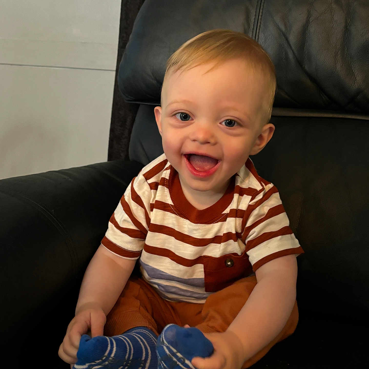 Asher is registered to the contest to win money with this photo: baby, babylaughing, bodypart, chair, clothing, couch, cushion, face, finger, furniture, glove, hand, happy, head, hosiery, person, photography, portrait, sitting, sock