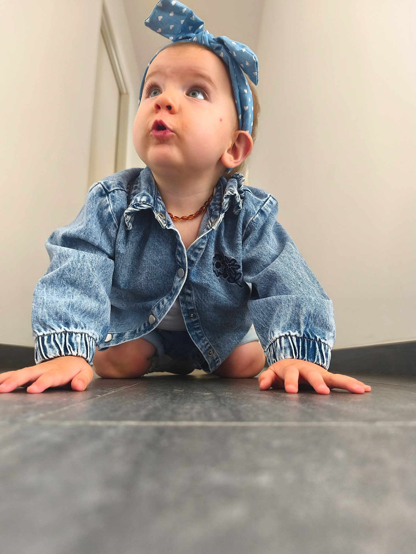Sophia participe au concours pour gagner de l'argent avec cette photo : toddler, child, denim_jacket, headband, indoor, floor, crawling, curious, expression, blue_headband, casual_clothing, person, young_child, wall, tile_floor, candid, baby, head, hands, jewelry