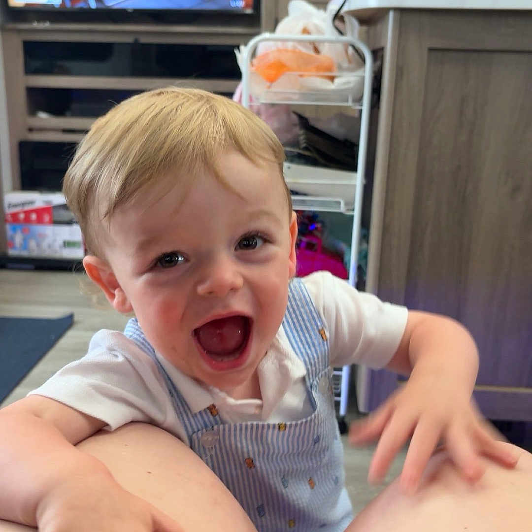 Lawson joined the competition — help win amazing prizes! toddler, child, happy, smiling, blue_striped_overalls, kitchen, television, furniture, person, indoor, hand, light_hair, short_hair, mouth_open, joyful, cabinet, countertop, floor, baby_bottle, home