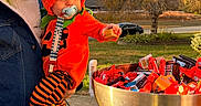 Lawson joined the competition — help win amazing prizes! adult, autumn, bowl, candy, car, child, costume, denim_jacket, grass, hand, holiday, orange, outdoor, pacifier, pumpkin_costume, sidewalk, sky, striped_pants, toddler, tree