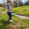 Lawson is registered to the contest to win money with this photo: casual_clothing, child, creek, curious, daytime, flower, grass, greenery, jeans, nature, outdoor, park, person, shirt, spring, sunlight, toddler, tree, white_shoes, young_child