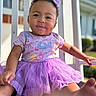 baby, child, infant, portrait, smiling, happy, outdoor, porch, purple_dress, tutu, bow, curly_hair, sitting, dress, floral_pattern, barefoot, sunlight, railing, closeup, cute