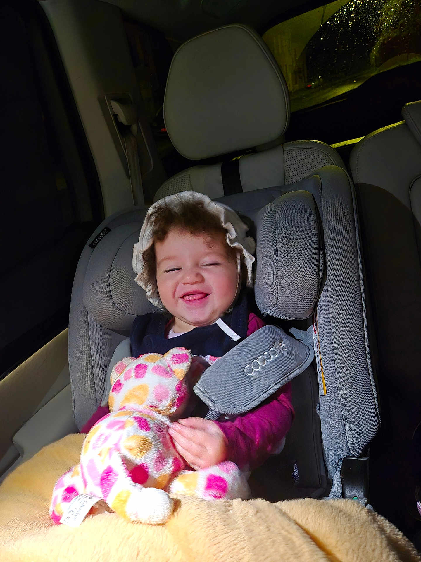 Sara participe au concours pour gagner de l'argent avec cette photo : toddler, child, car_seat, stuffed_animal, blanket, bonnet, smiling, happy, indoors, seat_belt, car_interior, night, curly_hair, clothing, person, toy, safety, seat, baby, cute