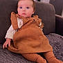 Rose participe au concours pour gagner de l'argent avec cette photo : baby, child, blue_eyes, brown_dress, tights, couch, indoor, soft_texture, curly_hair, cute, seated, portrait, cozy, furniture, home, infant, looking_away, clothing, warm_lighting, expression