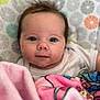baby, infant, face, blanket, pink, blue, white_clothing, patterned_background, curious, closeup, child, cute, soft_texture, indoors, pacifier_clip, expression, head, small_hands, toddler, young_child