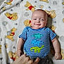 baby, child, infant, smile, striped_shirt, dinosaur_print, hand, blanket, winnie_the_pooh, cartoon, pattern, lying_down, cute, happy, indoors, soft_toys, playful, portrait, clothing, person