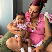 Laila joined the competition — help win amazing prizes! baby, child, couch, cute, family, green_couch, hair_bun, holding, indoor, infant, love, person, pink_clothing, portrait, relaxed, sitting, smile, socks, tattoos, woman