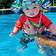 Roper joined the competition — help win amazing prizes! baby, child, pool, water, sun_hat, swim_shirt, hand, outdoor, summer, reflection, blue, red, person, face, skin, nature, sunlight, trees, swimming, cute