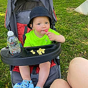 Lyzio a rejoint le concours — aidez-le/la à gagner de superbes lots ! toddler, child, stroller, bucket_hat, lollipop, water_bottle, snacks, outdoor, grass, green_shirt, blue_shoes, legs, sunny, baby, seatbelt, plastic_tray, park, summer, cute, happy