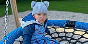 Lyzio a rejoint le concours — aidez-le/la à gagner de superbes lots ! child, toddler, swing, playground, rope_swing, blue, hat, knit_hat, bear_ears, snowsuit, shoes, outdoor, grass, trees, fence, daylight, curious, seated, play, park