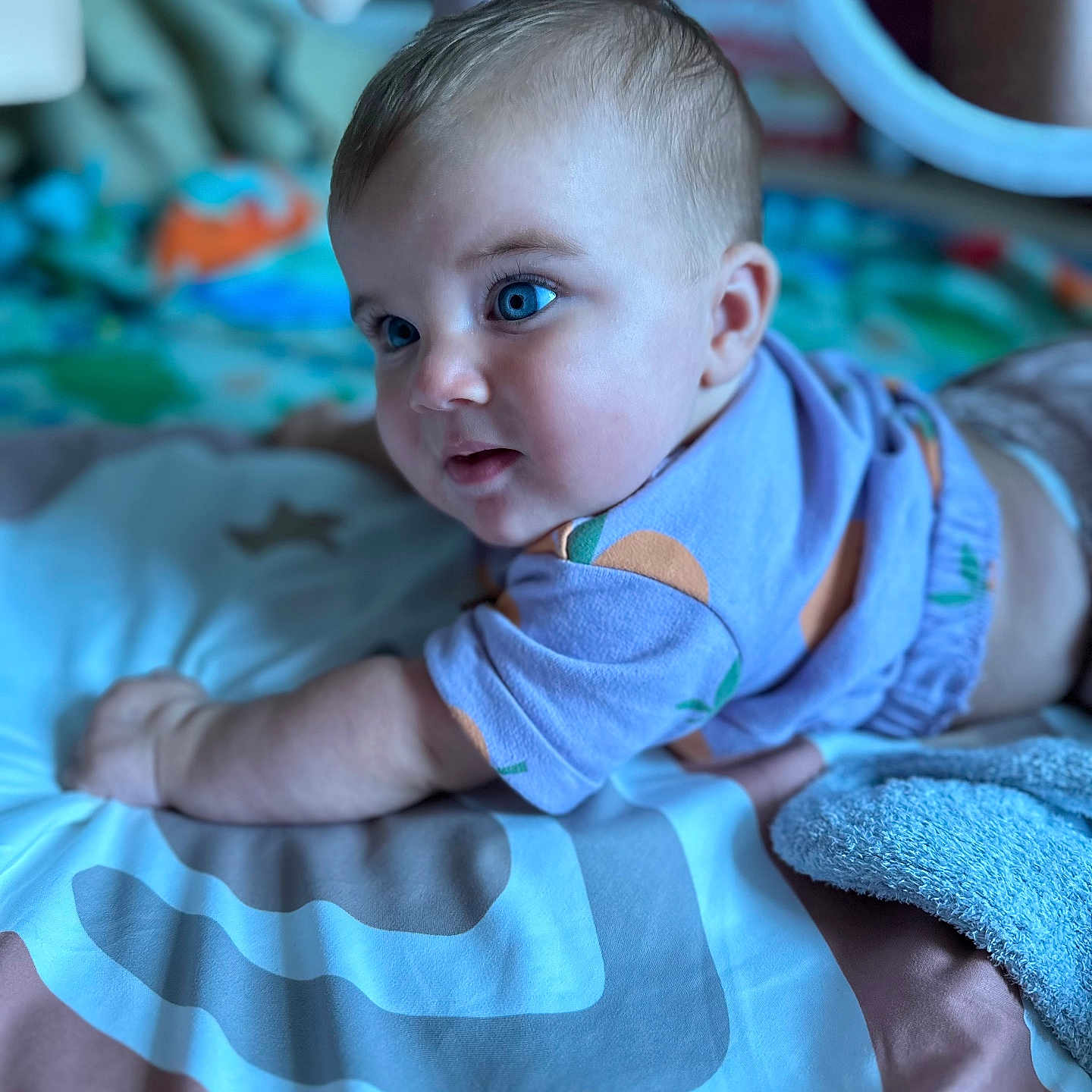 Gianna Meadow is registered to the contest to win money with this photo: arm, baby, blanket, blue_eyes, child, closeup, curious, face, hair, indoor, infant, lying_down, orange_pattern, play_mat, portrait, purple_shirt, skin, soft_light, toddler, toy