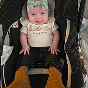 accessory, adorable, apparel, baby, boots, car_seat, child, closeup, clothing, cute, fabric, happy, headband, indoors, infant, jeans, person, portrait, seat, smiling