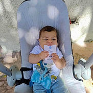 Yassine participe au concours pour gagner de l'argent avec cette photo : baby, infant, baby_seat, plush_toy, outdoor, sunlight, shadow, card, holding, cute, child, clothing, shorts, white_shirt, face, expression, toy, comfort, seat, playful