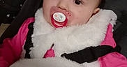 Iris a rejoint le concours — aidez-le/la à gagner de superbes lots ! baby, infant, pacifier, blanket, clothing, vest, pink, face, child, portrait, cute, seated, indoor, warm, cozy, fur, straps, expression, person, closeup