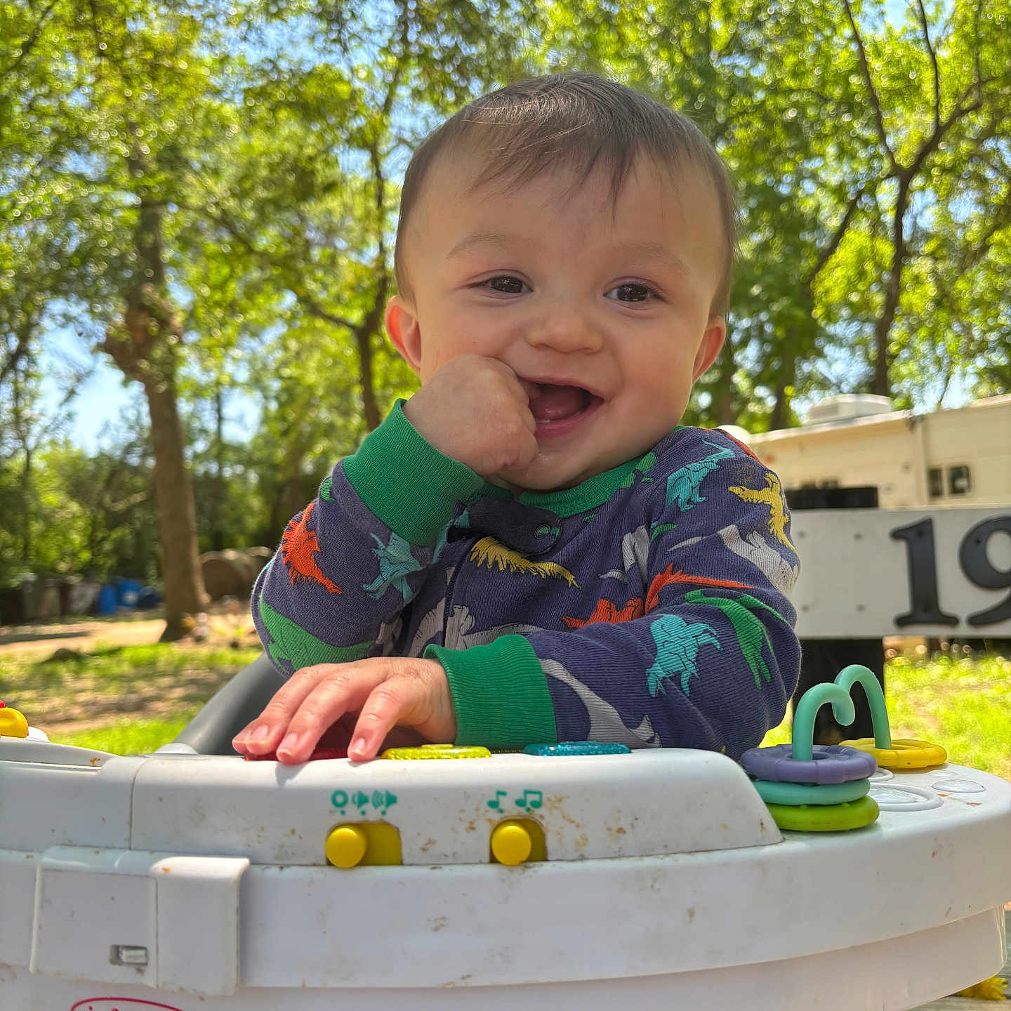 Rustyn joined the competition — help win amazing prizes! baby, child, closeup, colorful_clothing, daylight, dinosaur_onesie, greenery, happy, infantino, nature, outdoor, park, person, playful, portrait, smiling, sunlight, toy, trees, walker