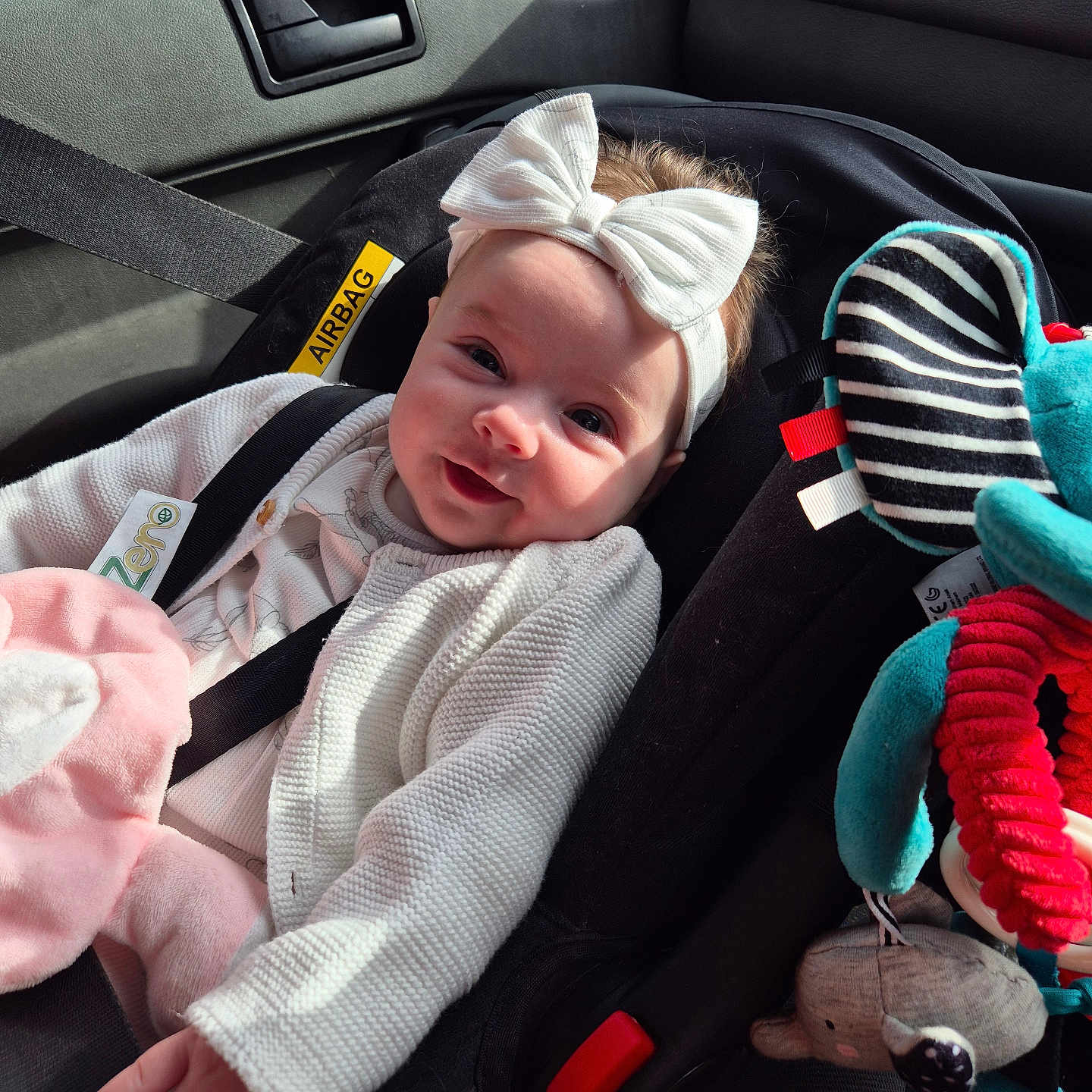 Isabella is registered to the contest to win money with this photo: baby, bow, car_interior, car_seat, child, child_safety, cute, happy, headband, infant, plush_toy, portrait, safety, seat, seatbelt, smile, sunlight, toy, vehicle, white_clothing