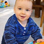 Joshua a rejoint le concours — aidez-le/la à gagner de superbes lots ! toddler, child, blue_sweater, smiling, toy, indoor, home, playful, happy, face, person, knitwear, buttoned_sweater, floor, window, daylight, furniture, hands, cute, young_child