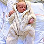child, newborn, infant, baby, sleeping, cozy, onesie, hood, fur_jumpsuit, zipper, blanket, pillow, bed, soft_texture, curled_hands, closed_eyes, peaceful, pale_skin, indoor, portrait