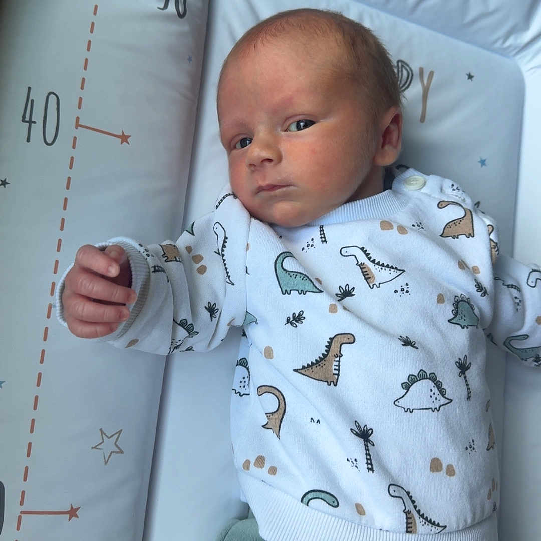 Thaylo a rejoint le concours — aidez-le/la à gagner de superbes lots ! baby, blanket, changing_mat, cozy, dinosaur_print, eyes_open, hand, head, infant, looking_at_camera, lying_down, measurement_marks, newborn, nursery, onesie, pajamas, portrait, skin, sleepy, soft_lighting