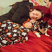 Bruce joined the competition — help win amazing prizes! animal, bed, black_and_white_cat, cat, cozy, cuddling, cute, ghost_pattern, halloween_theme, home, indoor, minnie_mouse, pajamas, person, pillow, pumpkin_pattern, red_bedspread, resting, smiling, spiderweb_pattern