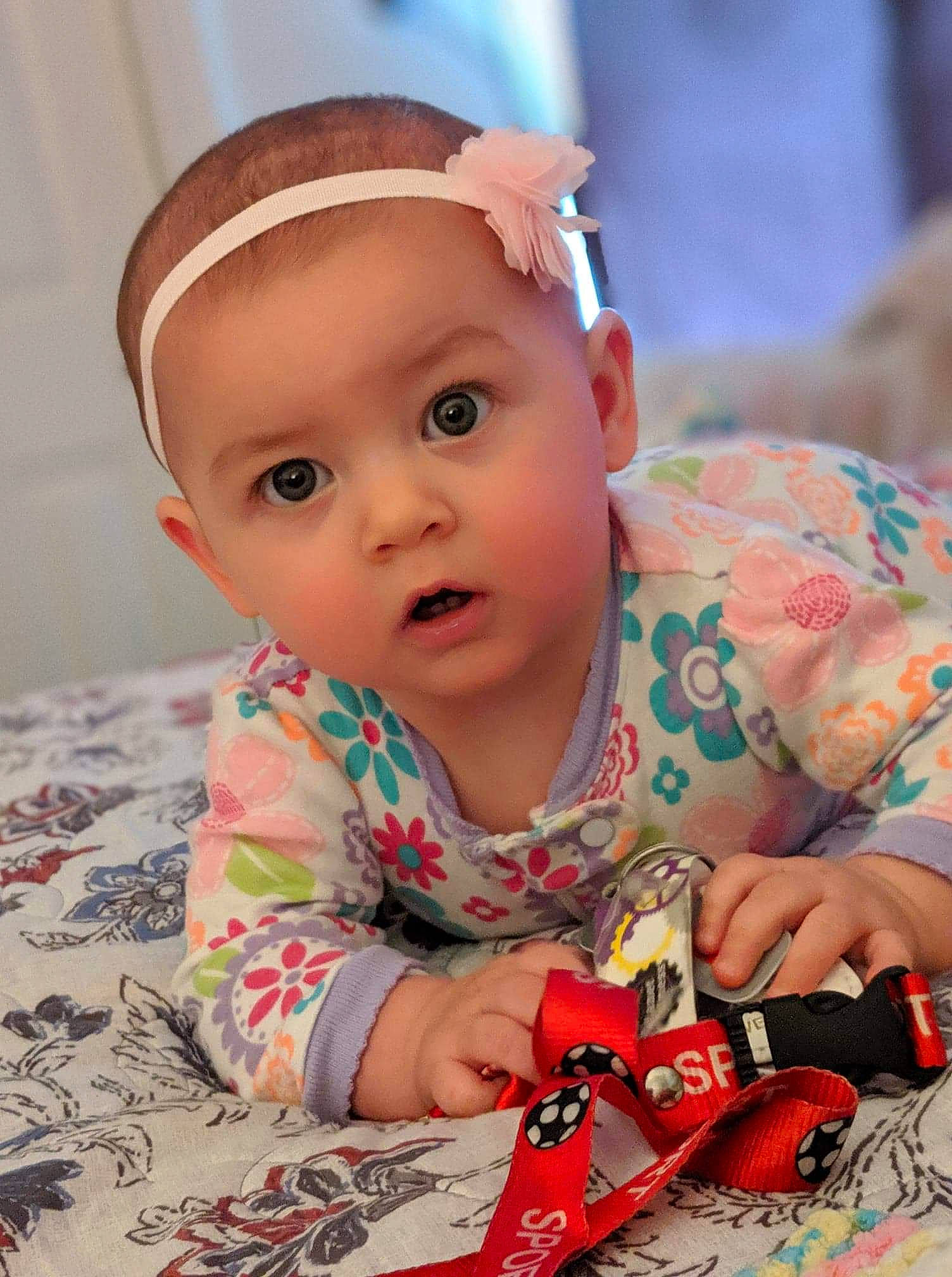 Adeline is registered to the contest to win money with this photo: baby, cheek, child, ear, eye, face, hair_accessory, head, headband, person, play, sitting, skin, smile, surprise, toddler