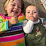 child, baby, smiling, laughing, floor, wooden_floor, rainbow_stripe, sweater, green_outfit, winnie_the_pooh, infant, happy, cute, two_kids, closeup, portrait, indoor, candid, playful, fist_in_mouth