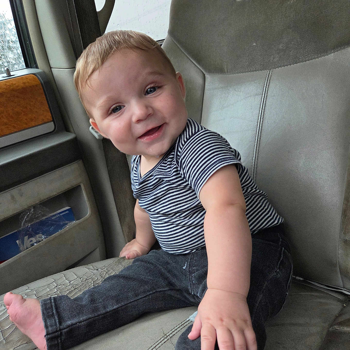 Huxley joined the competition — help win amazing prizes! baby, child, smiling, striped_shirt, jeans, car_seat, leather, drool, cute, happy, portrait, sitting, indoors, window, hand, foot, face, person, infant, casual