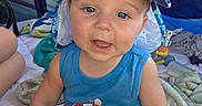 Huxley is registered to the contest to win money with this photo: baby, child, blue_clothing, hat, camouflage, tent, blanket, toy, indoor, smiling, sitting, face, person, infant, cute, summer, headwear, expression, playtime, light