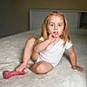 child, girl, toddler, portrait, smiling, sitting, bed, blanket, white_clothing, blonde_hair, braids, blue_eyes, dumbbell, toy, indoors, bedroom, fluffy, photography, watermark, fitness