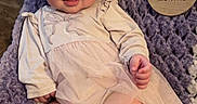 Anevay is registered to the contest to win money with this photo: baby, infant, smiling, headband, tutu, blanket, purple, white, cute, chubby, legs, hands, face, portrait, indoor, happy, young_child, clothing, sitting, soft_texture