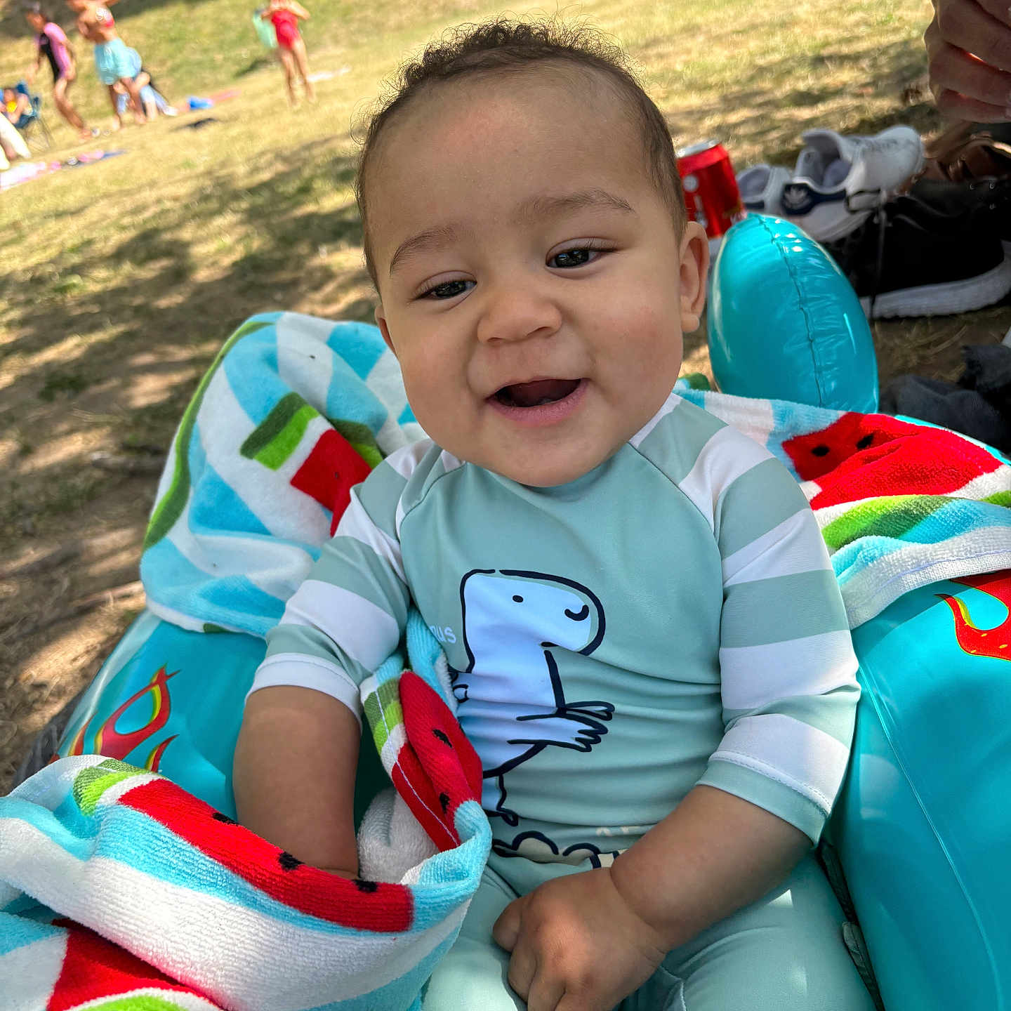 Dahion Rios a rejoint le concours — aidez-le/la à gagner de superbes lots ! baby, child, dinosaur, family, grass, happy, inflatable_chair, outdoor, park, people, play, relaxing, shoes, smiling, summer, sunlight, swimsuit, toddler, towel, watermelon_pattern